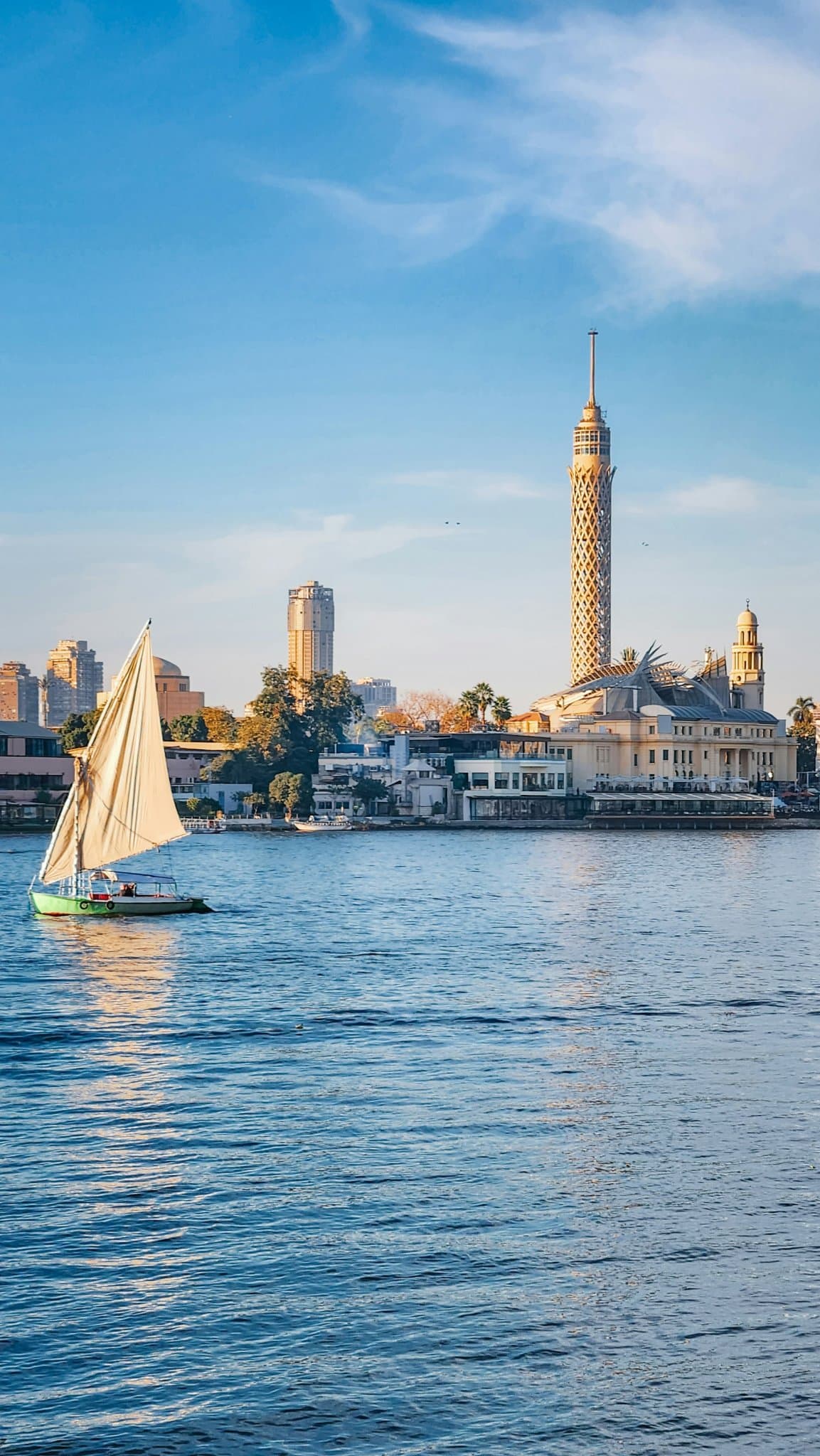 A traditional felucca sailing on the Nile with the Cairo skyline in the background.